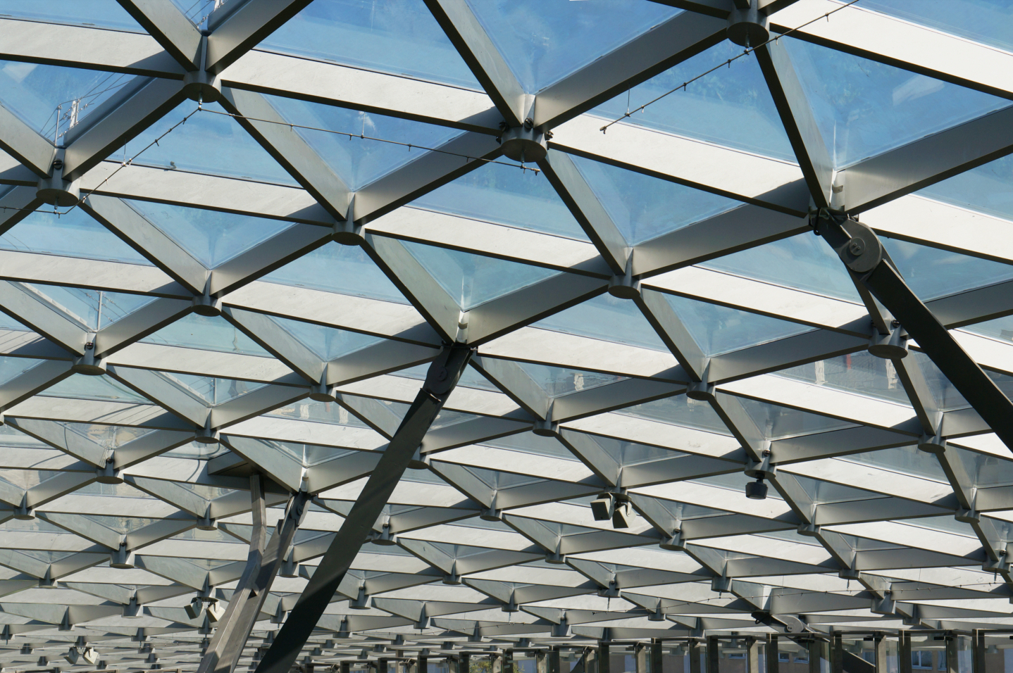 Die Glasdecke des modernen Gebäudes trägt ein Gitter aus Stahlträgern. Panoramacollage aus mehreren Innenaufnahmen